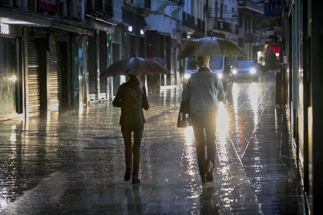 Imagen de archivo de dos personas se protegiéndose de la lluvia con un paraguas . EFE/Natxo Francés/Archivo