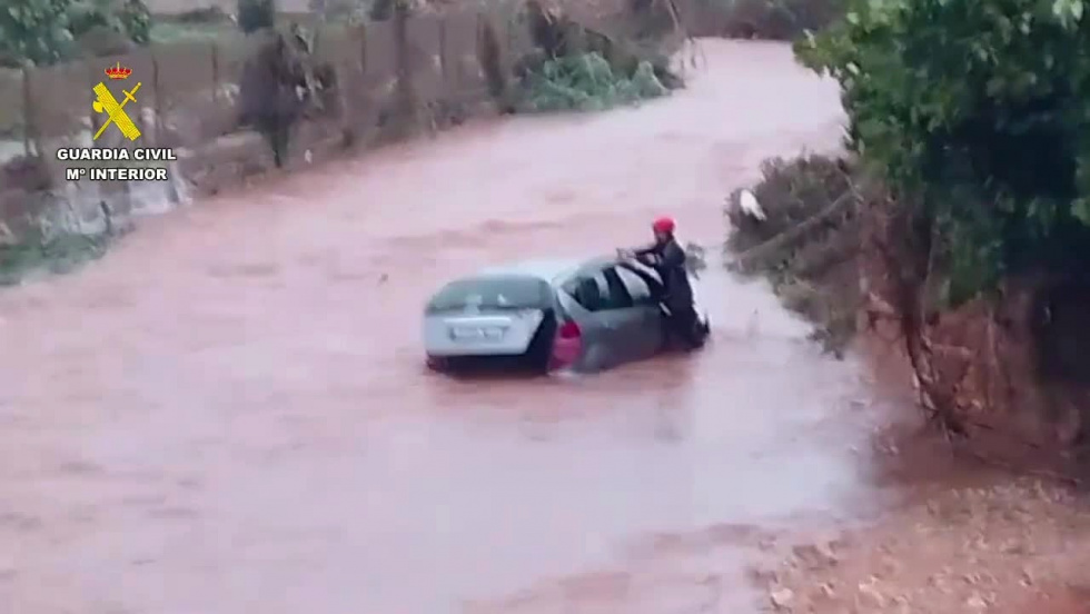 Un agente auxilia a un conductor en una zona anegada de la Marina Alta.